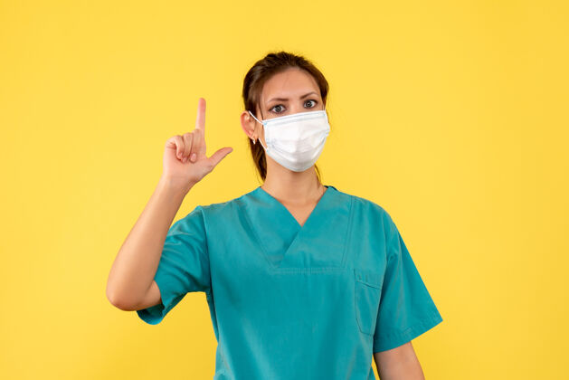 脸前视图黄色背景上穿着医用衬衫和面罩的女医生视图正面女医生