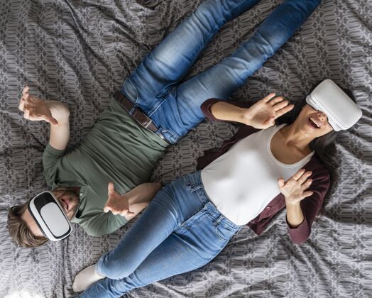 享受俯视图的女人和男人使用虚拟现实耳机在床上虚拟现实耳机女性休闲