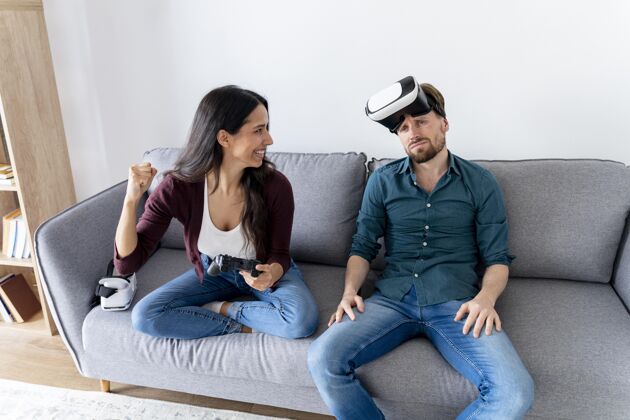 虚拟现实眼镜男人和女人坐在沙发上在家里与虚拟现实耳机休闲男人女人