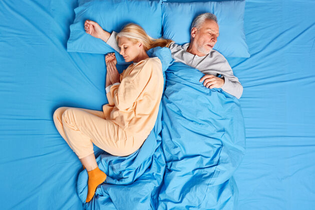 男人熟睡的已婚夫妇晚上深度睡眠 穿着睡衣享受宁静的氛围成熟的女人和男人在辛苦工作一天后小睡 感觉很舒服睡前概念欧洲和平睡眠