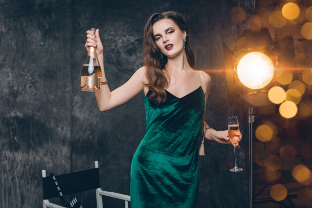 灯光年轻时尚性感的女人在电影院后台 用一杯香槟庆祝华丽女人微笑