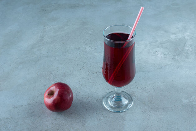 玻璃杯鲜红可口的果汁配新鲜的苹果和稻草素食者美食蔬菜