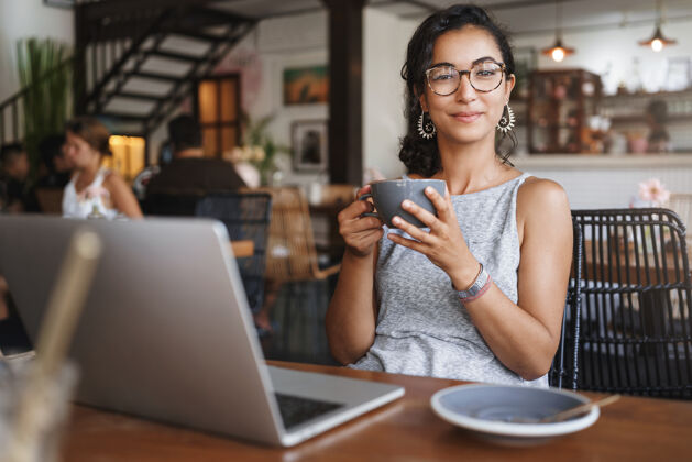 在线垂直拍摄温柔放松的都市女人戴着眼镜享受独自坐在咖啡馆的时刻现代办公室企业家