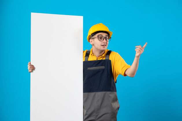 海报身穿黄色制服和头盔的男性建筑工人正视图 蓝色墙上有平面图工作人物正面
