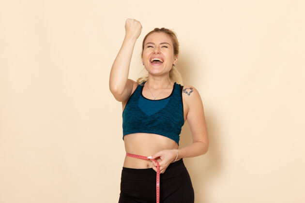 年轻女性前视图穿着运动装的年轻女性测量她的尺寸和腰围腰运动装