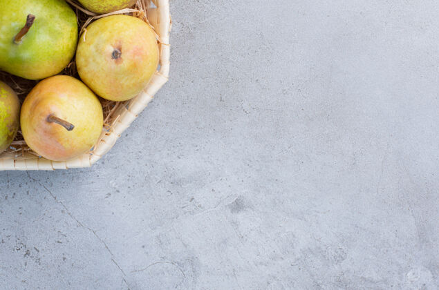 健康一小包各式各样的梨放在大理石背景的白色篮子里美味包水果