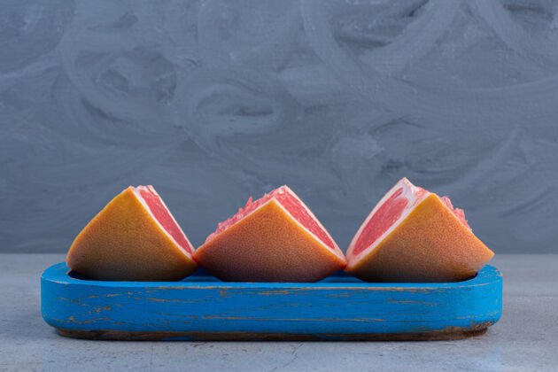 葡萄柚葡萄柚片放在大理石背景的蓝色小盘上拼盘美味水果