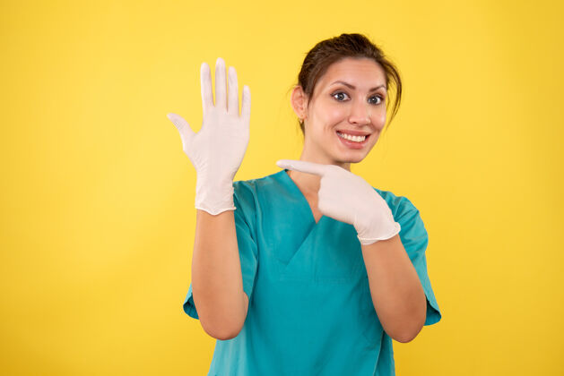 女医生前视图黄色背景上戴白手套的女医生微笑人成人