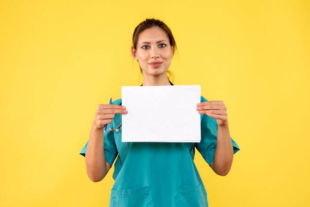 微笑正面图黄色背景下穿着医疗衫的女医生拿着纸分析前面女医生健康