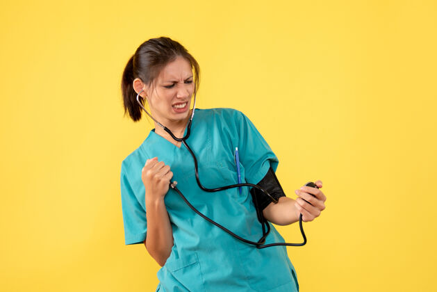 专业前视图穿着医用衬衫的女医生正在检查黄色背景上的压力压力女医生检查