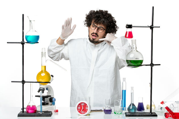 景观正面图身穿白色特殊套装的年轻男性科学家站在桌子旁 拿着解决方案特别实验室立场