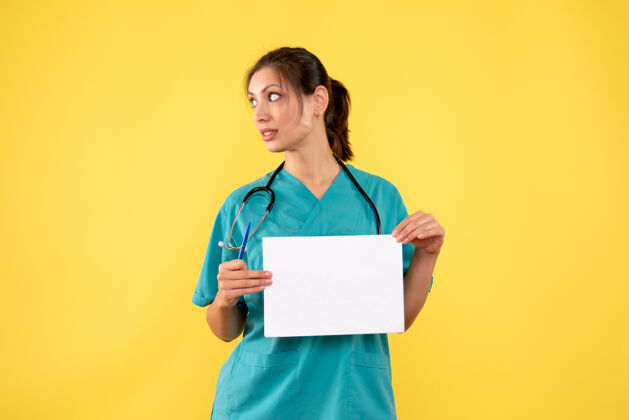 病毒正面图黄色背景下穿着医疗衫的女医生拿着纸分析人健康持有