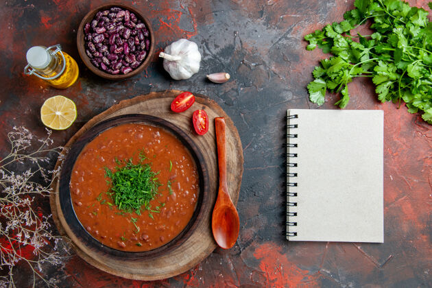 锅经典的番茄汤在一个棕色的碗里油瓶豆子和勺子上混色的桌子镜头午餐番茄汤欧芹