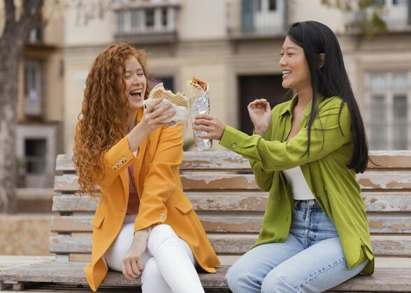 朋友快乐的女人一起吃街头美食食品垃圾食品街头食品