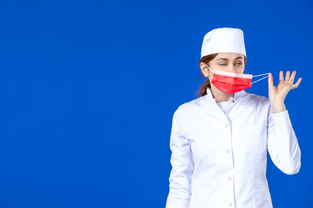 流行病身穿医疗服的年轻护士的正视图 蓝色的面具上有红色的面具病毒年轻护士衣服