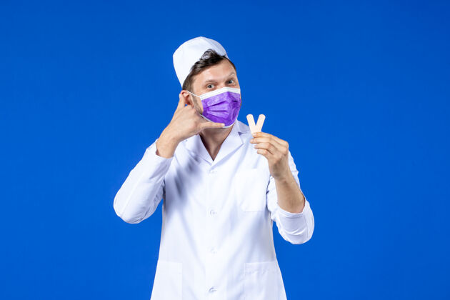疫苗前视图中的男医生穿着医疗服和面具举行小医疗补丁蓝色衣服男医生医院