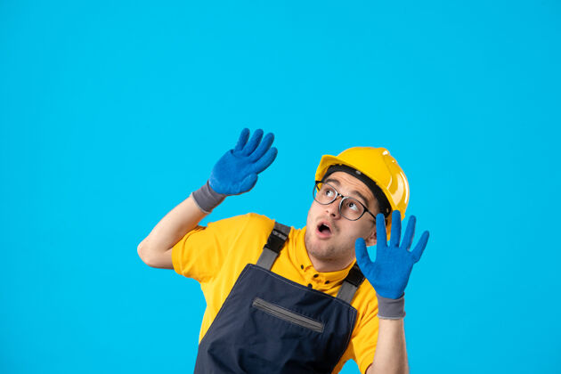 手套身穿制服 戴着蓝色手套的受惊男建筑工人的正视图表面工作制服