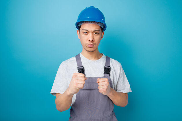 工人自信的年轻建筑工人戴着安全帽和制服做拳击动作制服安全年轻