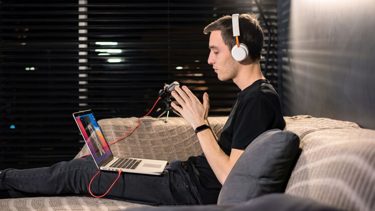工作年轻的内容创作者坐在沙发上 坐在笔记本电脑上 手牵手 在家工作屏幕监视器房子