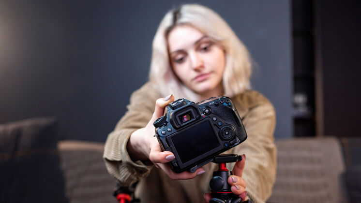 媒体年轻的内容创作者金发微笑的女孩把相机放在三脚架上在家工作开始拍摄视频博客虚拟博客互联网自由职业者