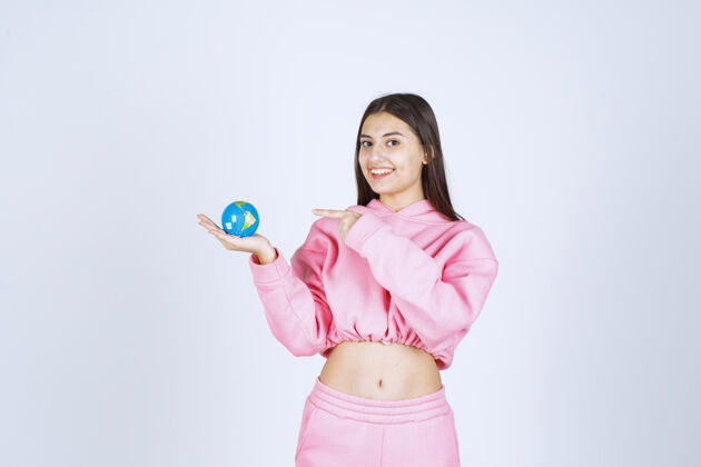 人体模型穿着粉色睡衣的女孩拿着一个迷你地球仪指着它姿势人职员
