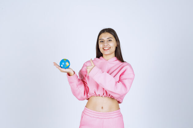 教育穿着粉色睡衣的女孩手里拿着一个迷你地球仪地图年轻人员工