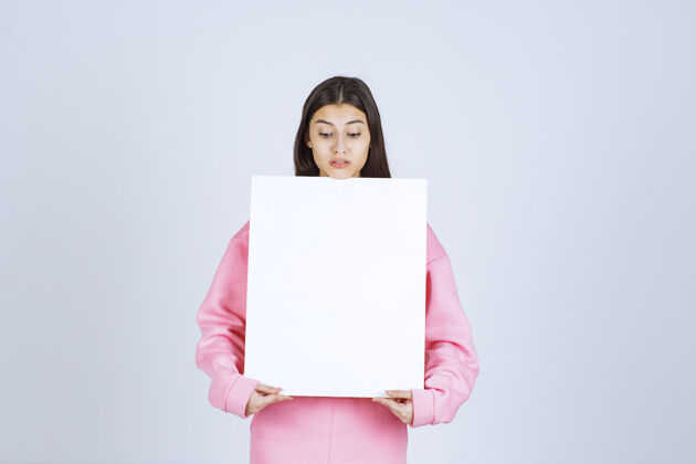 人体模特穿着粉色睡衣的女孩 手里拿着一块空白的方形展示板表演人类促销
