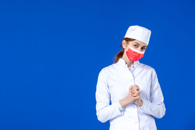 疾病压力重重的年轻护士的正视图 穿着医疗服 蓝色的面具上戴着红色的面具流行病西装疾病