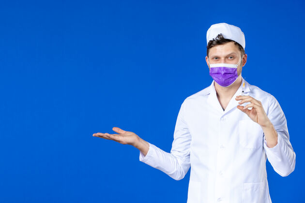 套装前视图中的男医生穿着医疗服和口罩持有疫苗和注射在蓝色药品注射医院