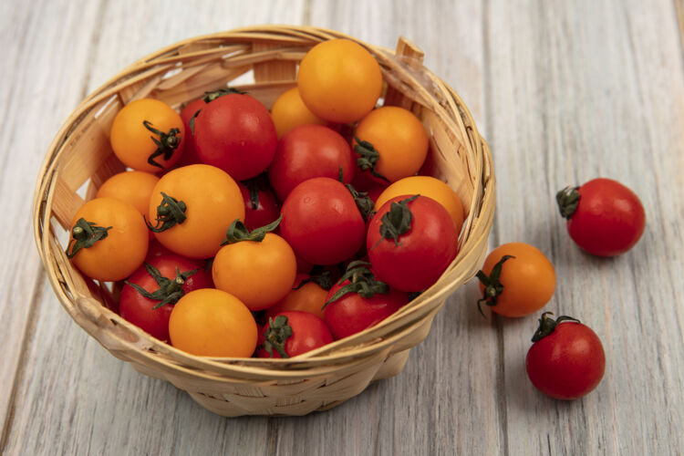 营养在灰色的木制表面上 桶上放着新鲜的红色和橙色的西红柿美味木材西红柿