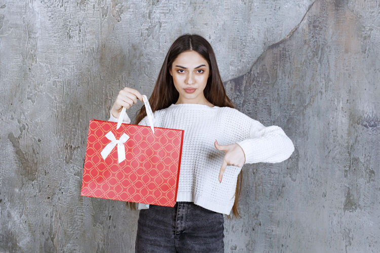 介绍穿白衬衫的女孩拿着一个红色购物袋 邀请旁边的人送礼物成人快递女售货员