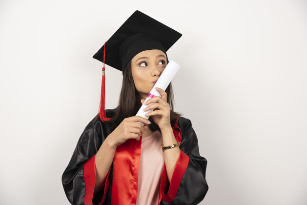 年轻应届毕业生在白色背景上亲吻毕业证书证书女性学术
