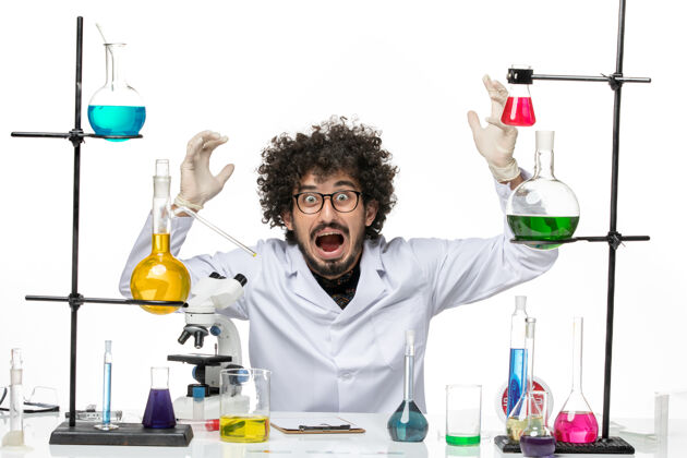 男化学家正面图身着医疗服的男性化学家正坐在桌子前面 浅白的空间里放着溶液科学医学医生