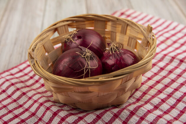美食新鲜的红洋葱的顶视图在一个桶上一个红色格子布在一个灰色的木制表面新鲜营养餐桌
