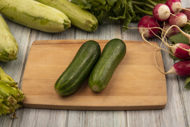 饮食顶视图新鲜黄瓜上的木制厨房板与萝卜西葫芦和芹菜隔离在一个灰色的木制表面美味素食厨房