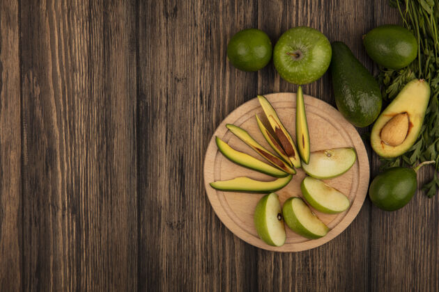 酸橙新鲜苹果片的俯视图在一个木制的厨房板上与整个苹果鳄梨片鳄梨酸橙和欧芹隔离在一个木制表面与复制空间欧芹新鲜水果