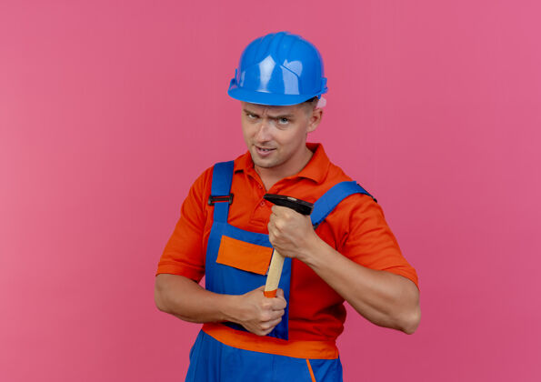 工人自信的年轻男性建筑工人穿着制服 戴着安全帽手持铁锤制服头盔信心