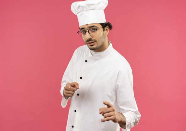 制服自信的年轻男厨师穿着厨师制服 戴着眼镜向你展示手势男士烹饪厨师