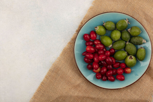 可口在灰色表面的布袋上 蓝色盘子上放着成熟的凤梨和樱桃 上面有复制空间食物营养饮食