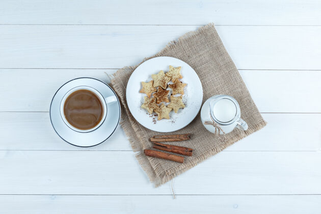新鲜食品顶视图咖啡杯饼干 肉桂棒 牛奶在木制和布袋的背景玻璃杯自助餐果酱