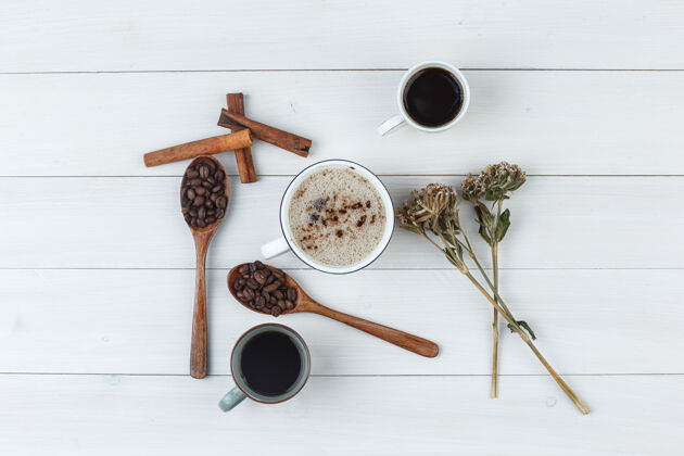 早晨一套咖啡豆 肉桂棒 干香草和咖啡杯在木制背景上顶视图质地味道杯子