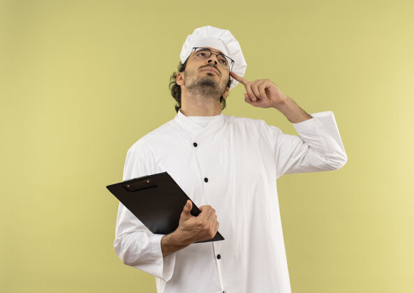 男看着一个穿着厨师制服 戴着眼镜 拿着剪贴板 手指放在额头上的年轻男厨师男厨师眼镜