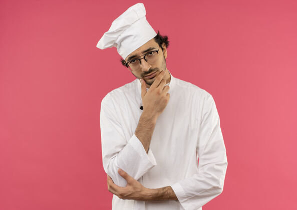 男人年轻的男厨师穿着厨师制服 戴着眼镜 手放在下巴上烹饪眼镜思考