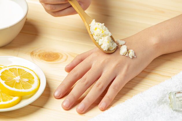 剥皮年轻女子用天然柠檬磨砂膏擦在木桌上清洁卫生皮肤科