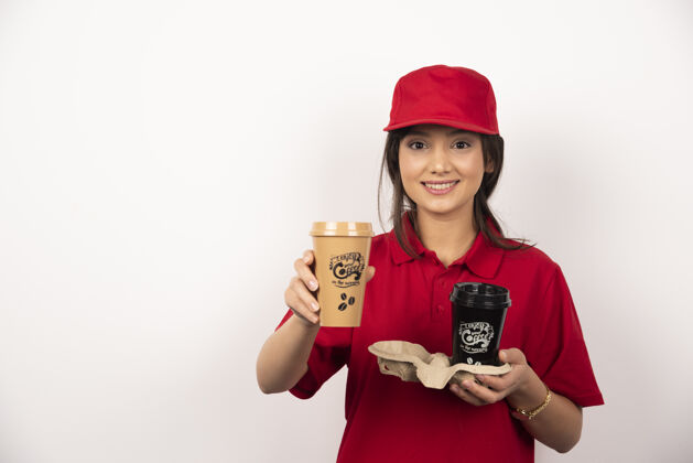 订单微笑的女信使拿着咖啡在白色背景上送货制服专业咖啡
