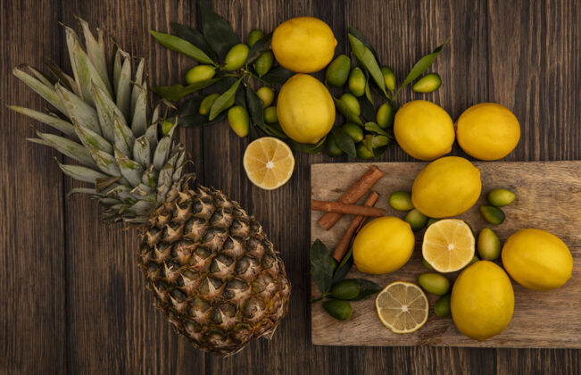 膳食新鲜水果的俯视图 如金盏花和柠檬 肉桂棒放在木制厨房板上 菠萝放在木制表面农业人厨房