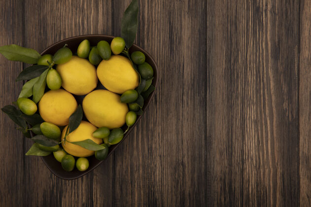 配料顶视图新鲜柑橘类水果 如柠檬和金盏花在一个木制表面与复制空间碗柠檬木材美味