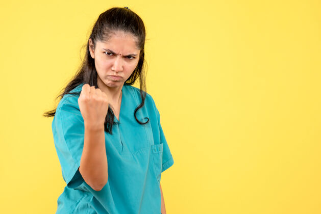 人正面图不满意的女医生穿着制服站在黄色孤立的背景上制服医学成人