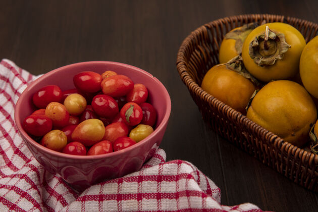柿子红色格子布上碗里的多汁凤梨樱桃俯视图 木桶上的柿子水果木材美味衣服