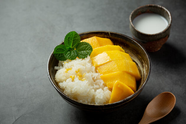 热带新鲜成熟的芒果和糯米 在黑暗的表面涂上椰子奶芒果米饭食物